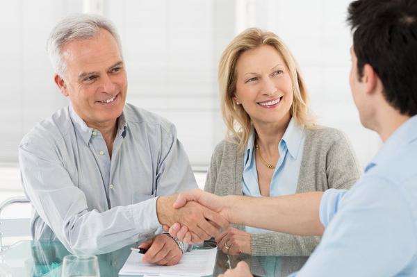 19339638 - senior happy couple shaking hand with financial advisor